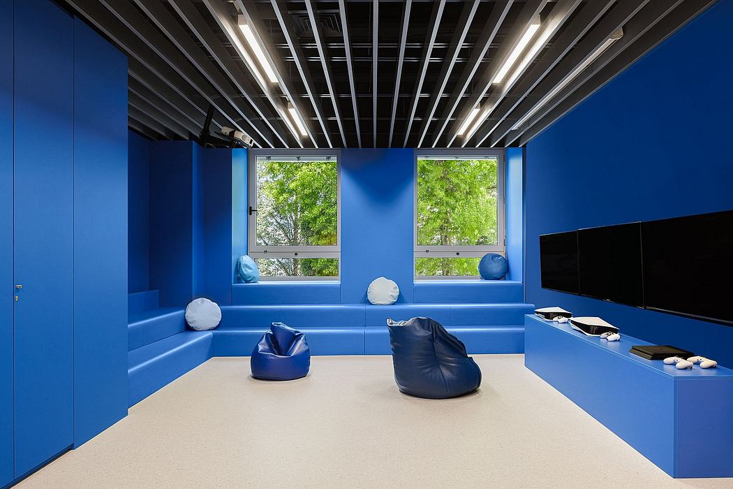 Sleek, modern interior with bright blue walls, black ceiling grid, and large windows overlooking nature.