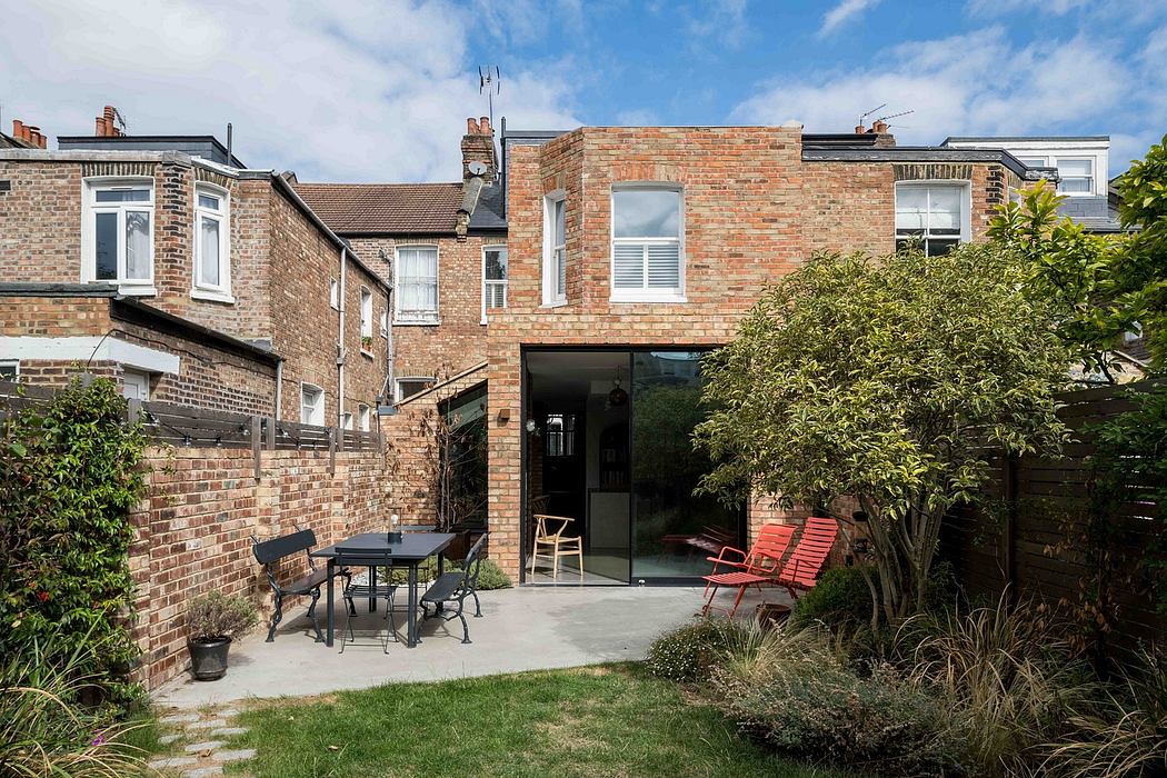 A charming brick townhouse with a modern glass extension and lush garden patio.
