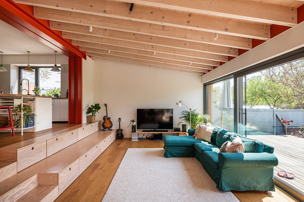 A cozy living room with wood-beamed ceilings, modular seating, and large windows offering garden views.