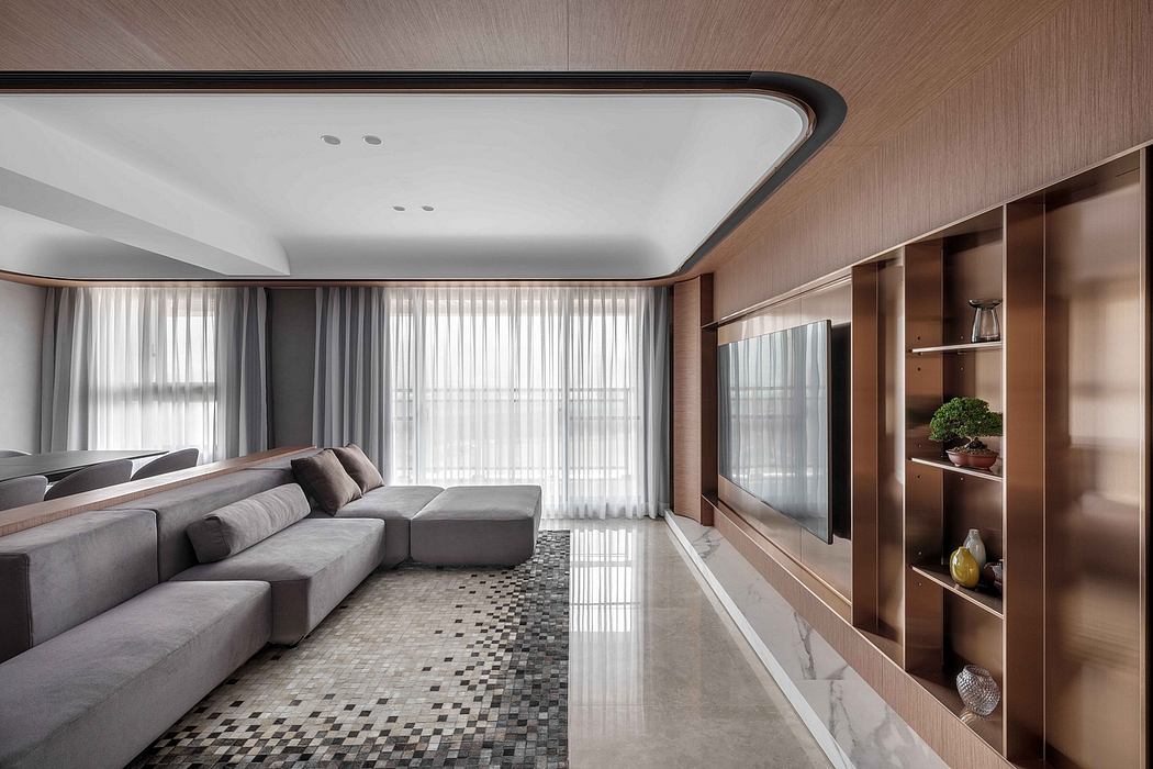 Elegant modern living room with sleek gray sofa, built-in shelving, and large windows.