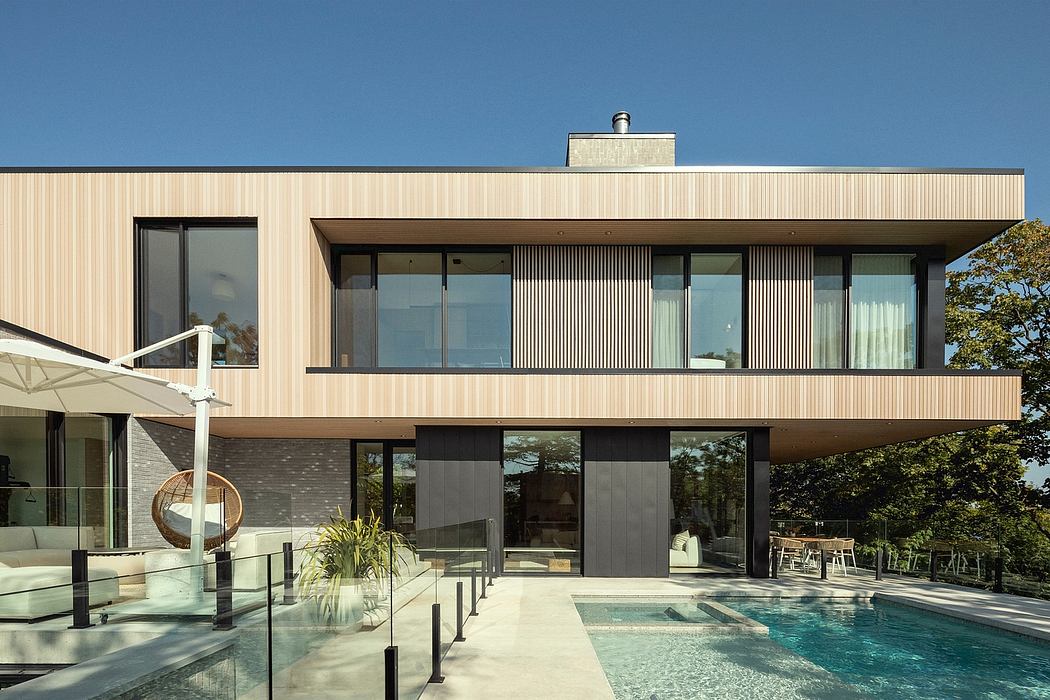 Sleek modern architecture with a glass-walled pool, terraced decks, and lush greenery.