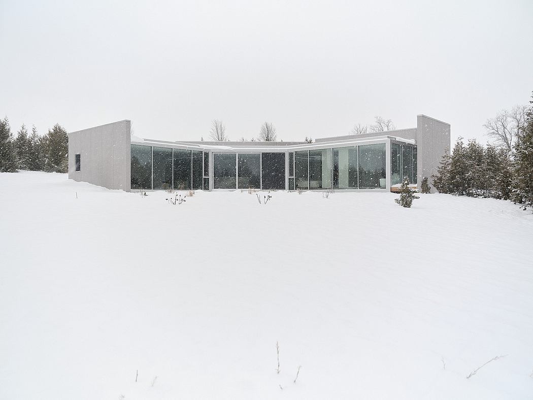 A modern glass-walled building with a curved facade, surrounded by a snowy landscape.