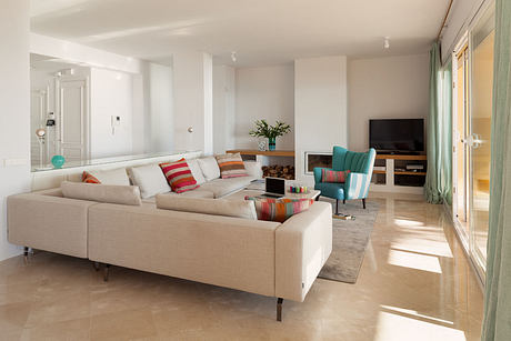 A bright, modern living room with beige sofa, colorful accents, and wood-burning fireplace.