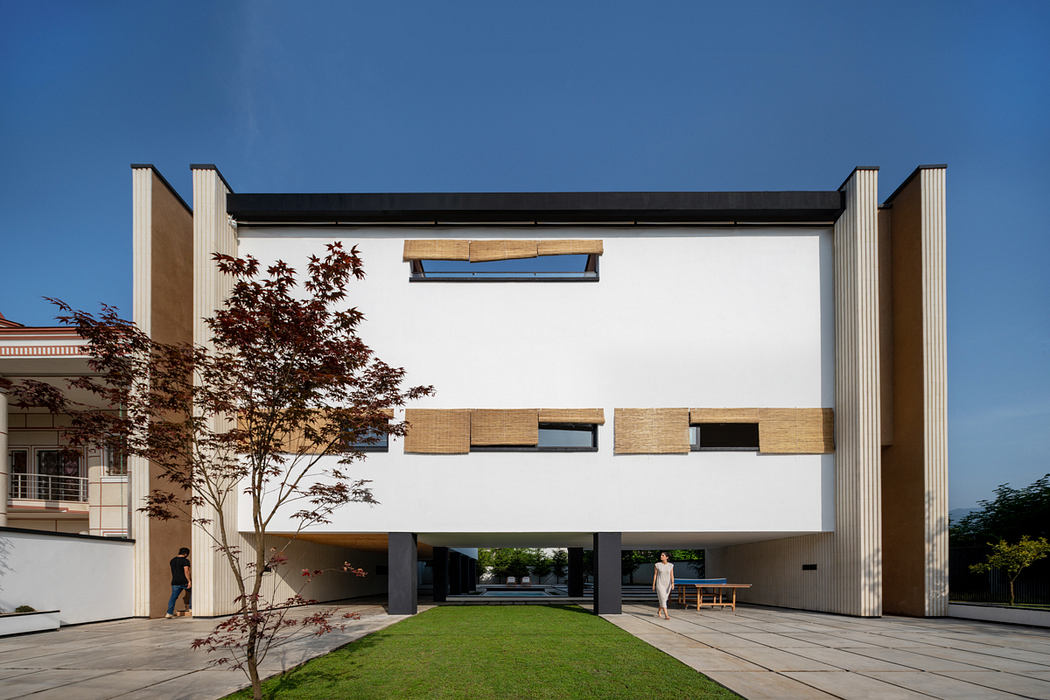 Modern, minimalist building with clean lines, wooden accents, and a grassy courtyard.