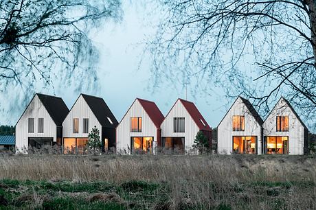 A row of modern, barn-like structures with large windows, set against a wintry landscape.