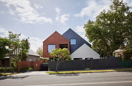 Modern residential home with red brick and gray-colored exterior, surrounded by trees.