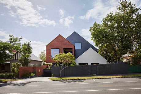 Modern residential home with red brick and gray-colored exterior, surrounded by trees.