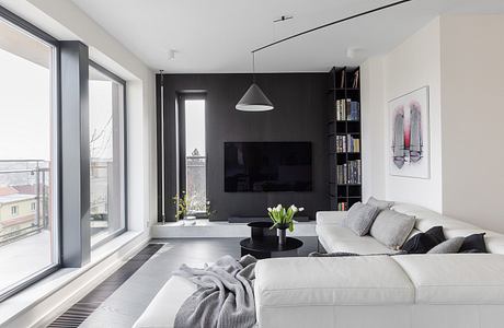 Sleek, modern living room with dark accent walls, built-in shelves, and large windows.