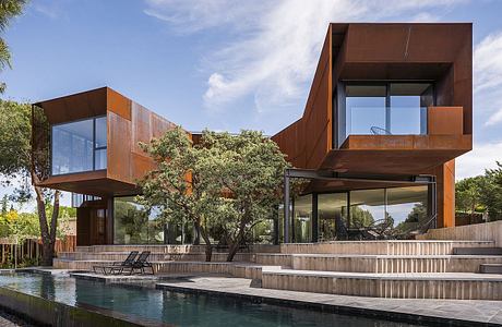 Striking modern architecture with copper-colored panels, glass walls, and multi-level design.