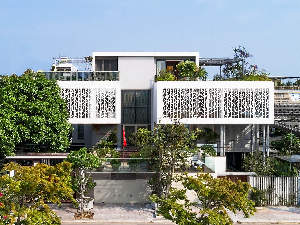 Modern multi-story building with intricate lattice balconies, surrounded by lush greenery.