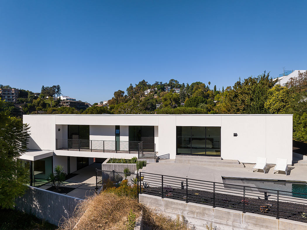 A sleek, modern home with floor-to-ceiling windows, terraced landscaping, and a pool.
