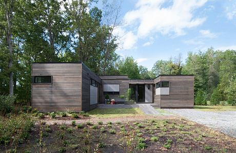 Modern wood-clad home with asymmetrical volumes, large windows, and a covered porch.