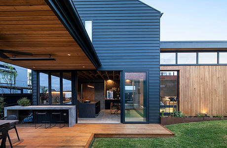 Contemporary wooden patio with glass walls, integrated outdoor area, and landscaped yard.