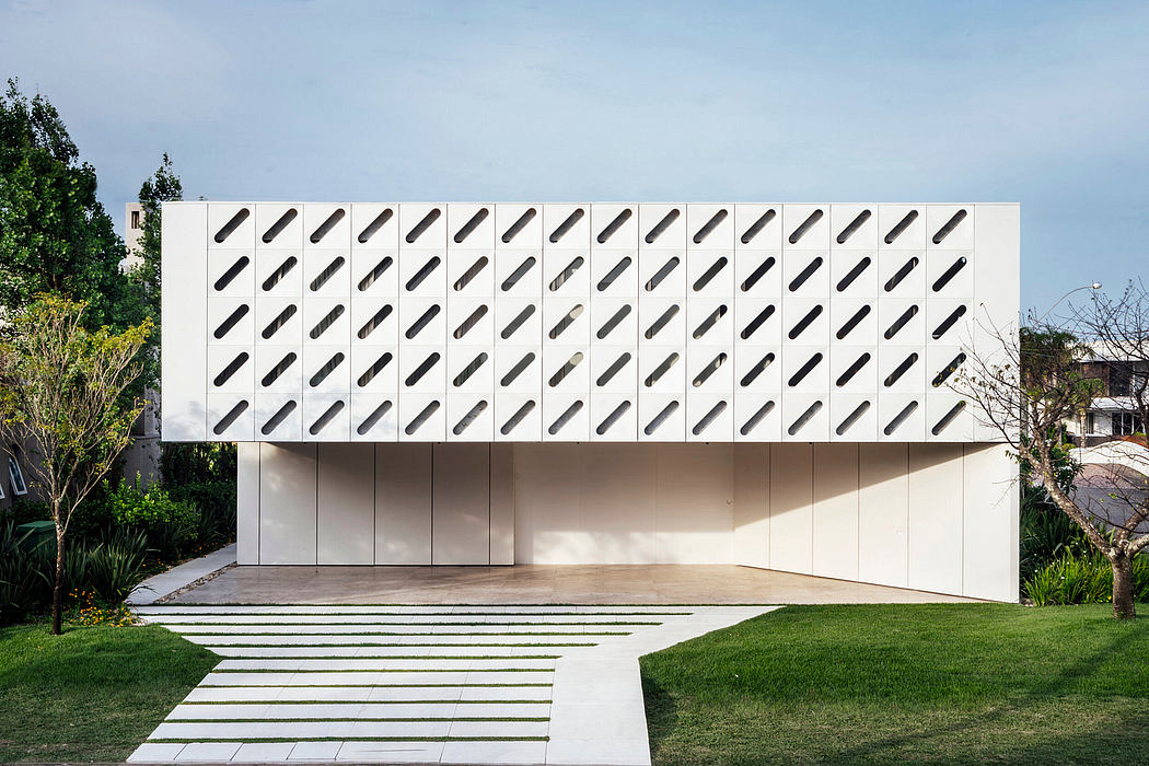 A modern architectural building with a striking white facade featuring a repeating pattern of black ovals.