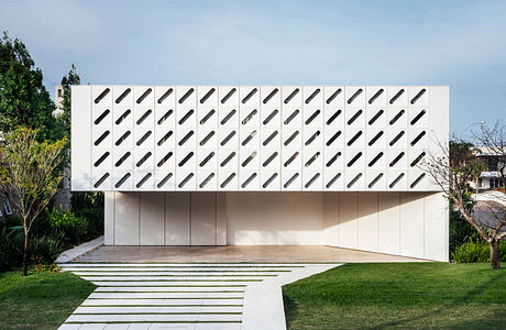 A modern architectural building with a striking white facade featuring a repeating pattern of black ovals.