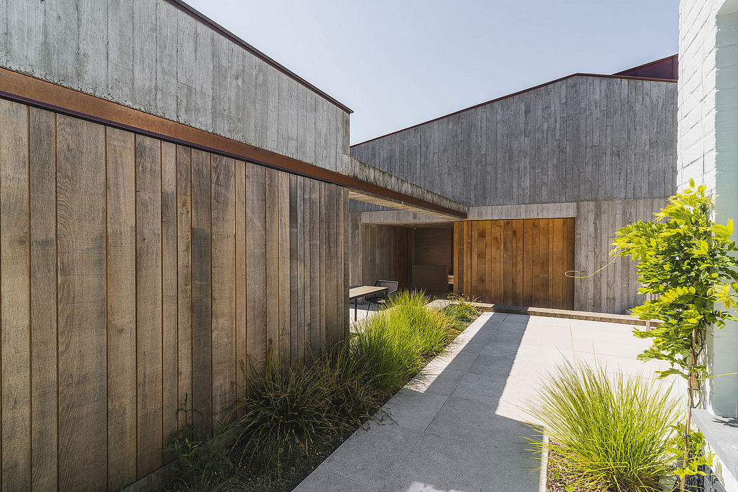 Weathered wooden paneling and concrete form an inviting outdoor passageway.
