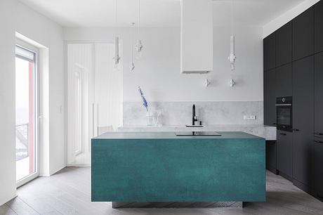 A modern kitchen featuring a sleek turquoise island, black cabinets, and pendant lighting.