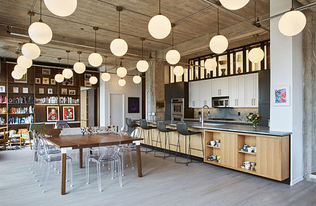 Spacious open-concept kitchen and dining area with pendant lighting, wood and concrete details.