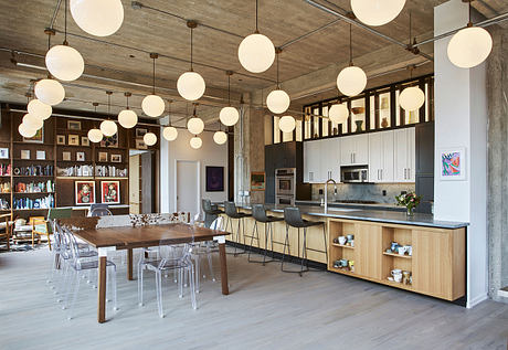 Spacious open-concept kitchen and dining area with pendant lighting, wood and concrete details.