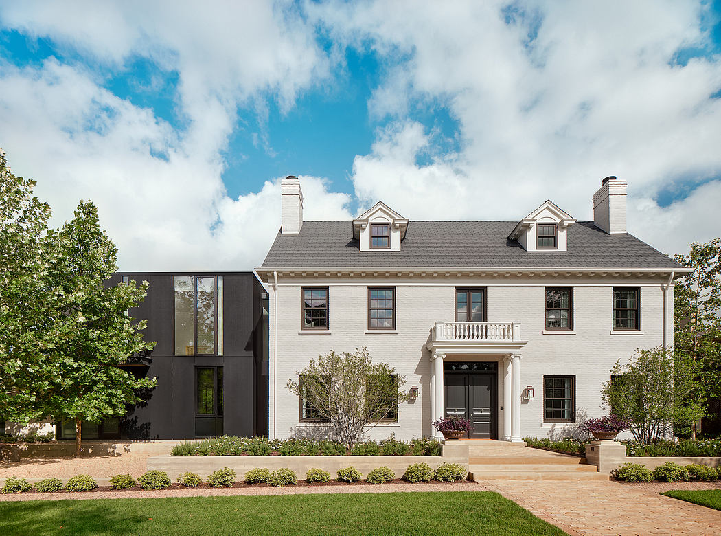 Elegant, two-story white colonial home with dormers, black accents, and manicured landscaping.