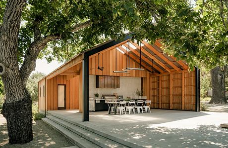 Spacious outdoor patio with a modern wooden structure, featuring an open-air kitchen and dining area.