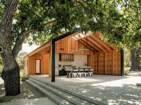 Spacious outdoor patio with a modern wooden structure, featuring an open-air kitchen and dining area.