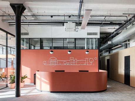 Modern industrial-style office lobby with a curved orange reception desk and a skyline-inspired graphic wall.