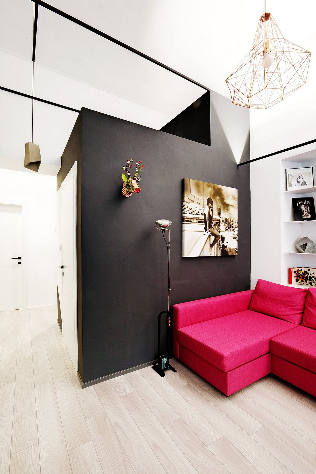 Sleek, modern interior with bold black walls, geometric lighting, and vibrant pink sofa.