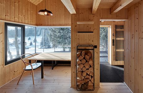 Cozy wood-paneled cabin with floor-to-ceiling windows, rustic furnishings, and fireplace.