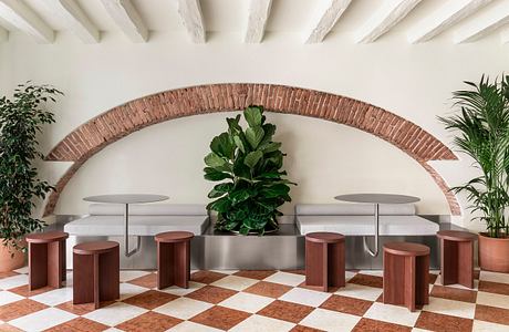 Elegant brick archway frames a modern seating area with potted plants.