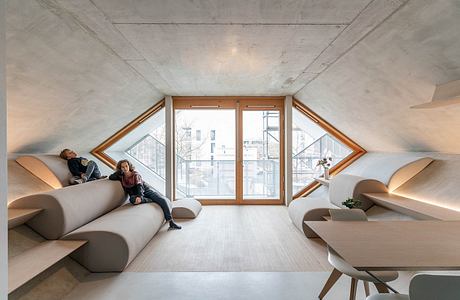 Striking attic space with angled windows, plush seating, and minimalist furnishings.