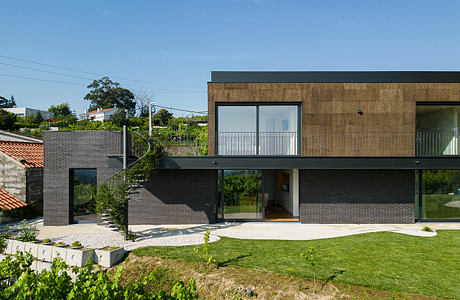 Modern residential home with contrasting brick and wood exterior, large windows, and landscaped yard.