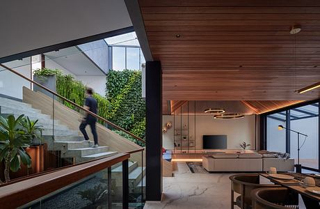 A modern interior with wooden paneling, glass walls, and a lush greenery backdrop.