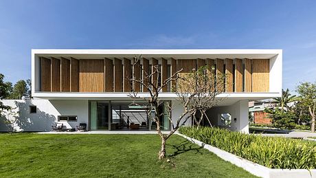 Minimalist architectural design with wooden facade, large glass windows, and lush landscaping.