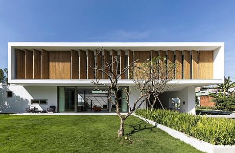 Minimalist architectural design with wooden facade, large glass windows, and lush landscaping.