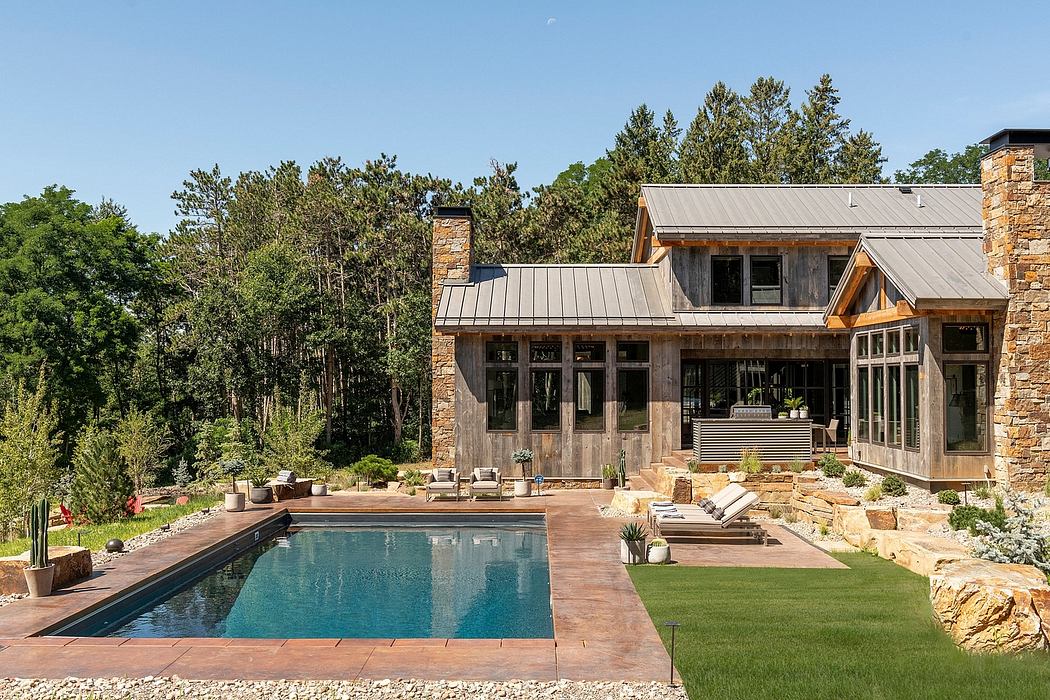 A rustic modern mountain home with a pool, stone and wood exterior, and lush landscaping.