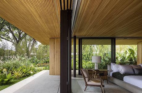 A modern wooden patio with sleek black frames, surrounded by lush greenery.