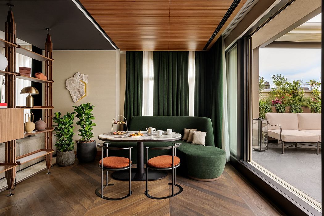 An elegant modern dining area with green velvet sofa, round wood table, and floor-to-ceiling windows.