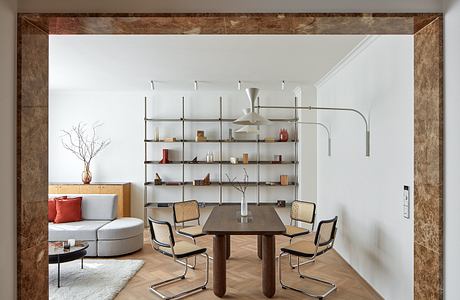 Minimalist dining area with sleek furniture, modern shelving, and warm lighting.