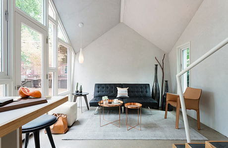 Cozy modern living room with vaulted ceiling, sleek furniture, and natural views.