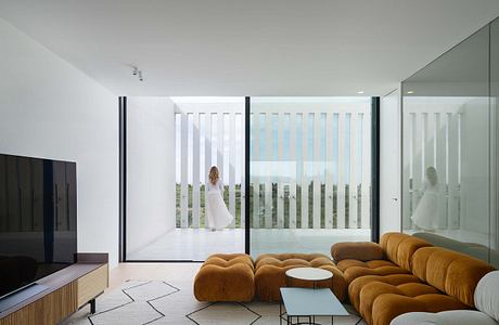 Minimalist living room with large windows, sleek furniture, and muted color palette.