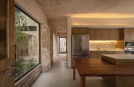 A modern, open-concept kitchen and dining area with rustic stone walls and wooden accents.