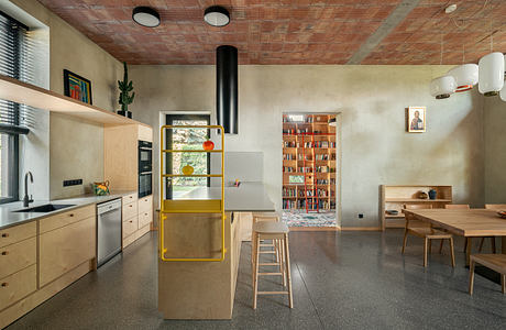 A modern kitchen with a yellow storage unit, wood-paneled ceiling, and open layout.