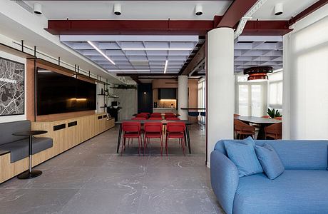 Modern open-plan workspace with sleek furnishings, recessed lighting, and a blue sofa.