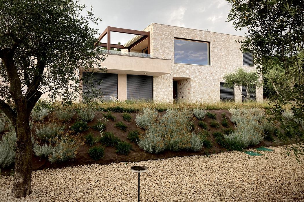A modern two-story home with a stone exterior, balcony, and lush landscaping.