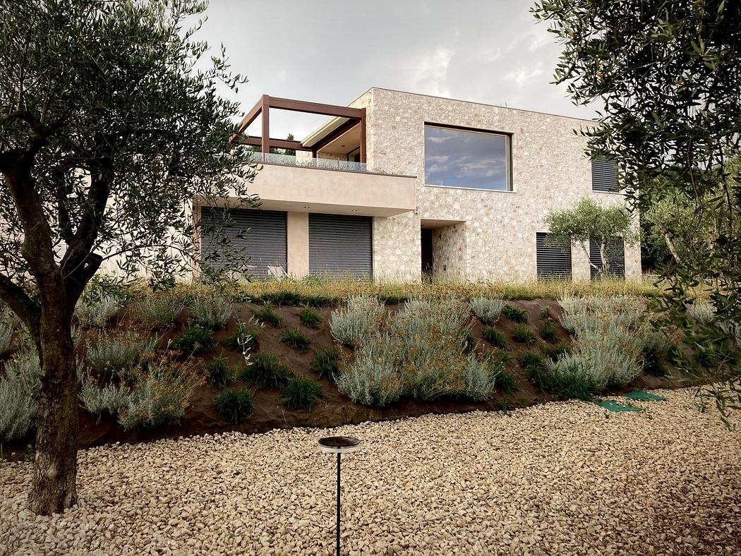 A modern two-story home with a stone exterior, balcony, and lush landscaping.