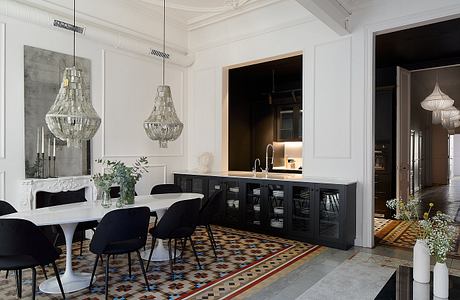 Elegant dining room with ornate chandeliers, patterned tile floor, and sleek black cabinetry.