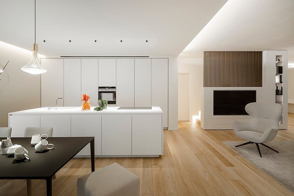 Sleek modern kitchen with white cabinetry, wood floors, and minimalist decor.
