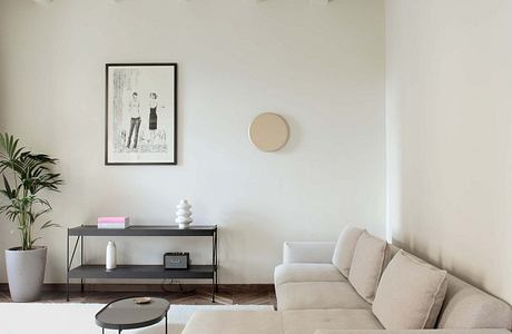 Minimalist living room with sleek shelving unit, plush sectional, and patterned wood flooring.