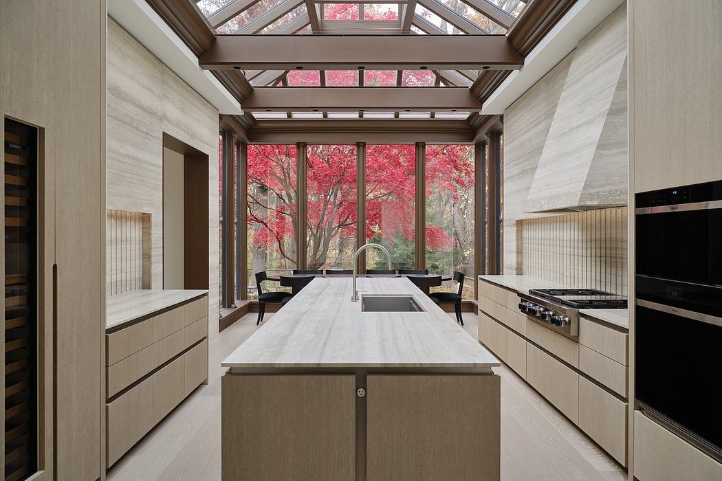 A modern kitchen with a glass-paneled ceiling framing vibrant fall foliage outside.